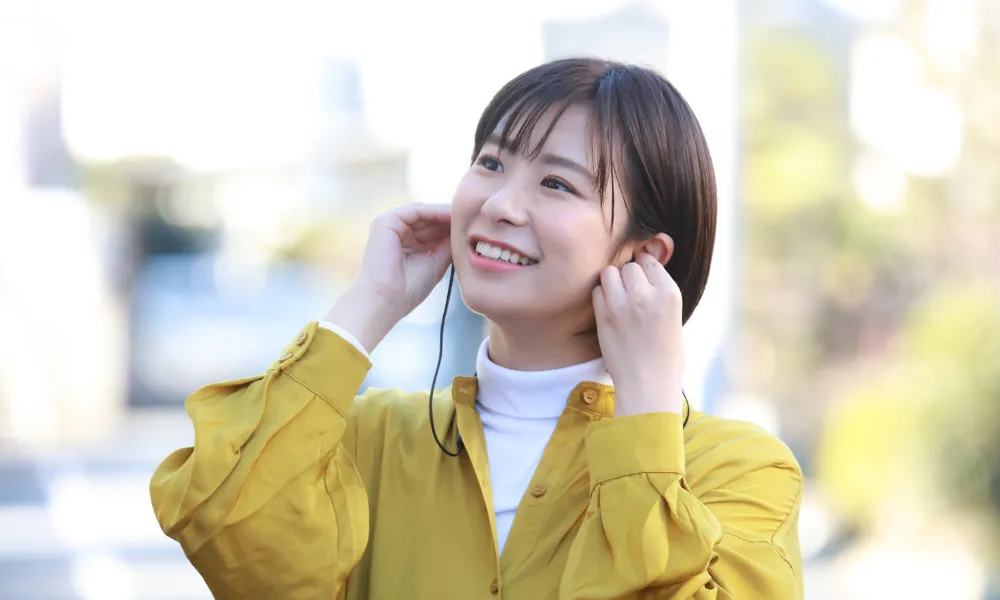 オープンイヤーイヤホンの音漏れを確認している女