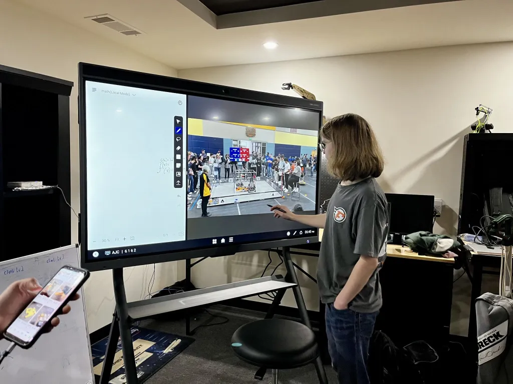The boy uses the smart screen to write on the board