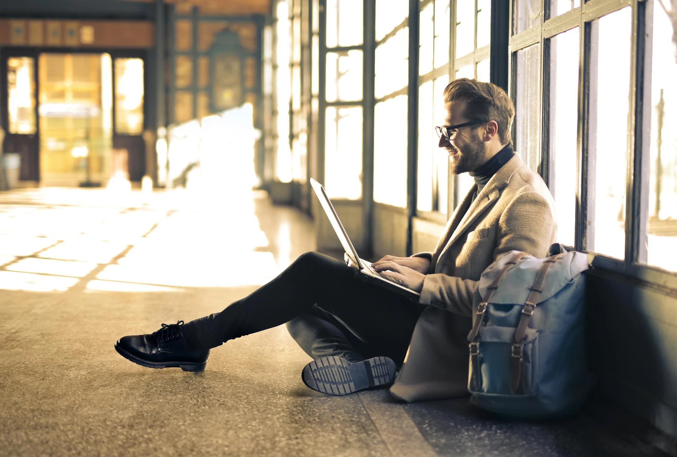 A man is sitting on the floor having a meeting on his computer