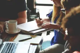 A-woman-taking-notes-at-a-meeting