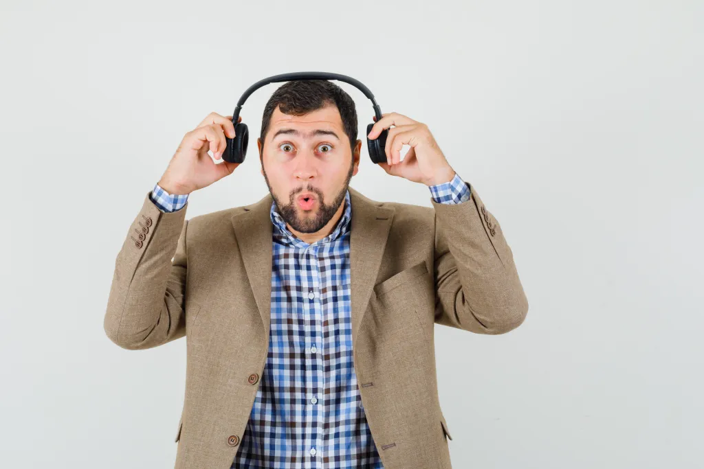 Confused man taking off traditional closed-back headphones