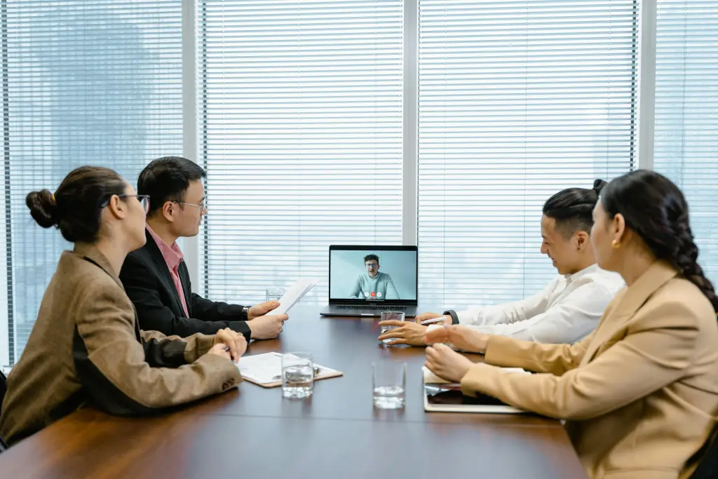Vier Personen halten eine Videokonferenz um einen Laptop herum ab.jpg