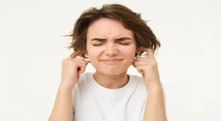 Woman covering her ears from loud noise and feeling uncomfortable