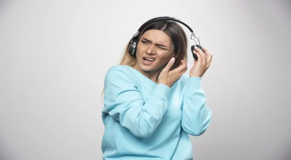 Woman experiencing discomfort while wearing over-ear headphones