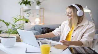 Woman wearing wireless headphones while working on a laptop at home.jpg