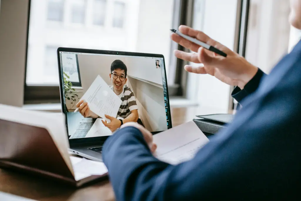 Zwei Personen halten ein Meeting mit Microsoft Teams Premium ab und demonstrieren dabei auf einem Whitepaper.jpg