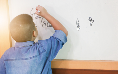 男の子が壁面ホワイトボードで字を書いています