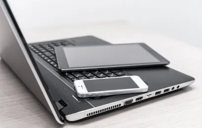 ノートパソコンの上に電子メモとスマートフォンが置かれている