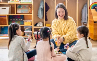 一人の女性教師が子どもたちと接し、異年齢保育の年間指導計画を理解し、作成しようとしています。
