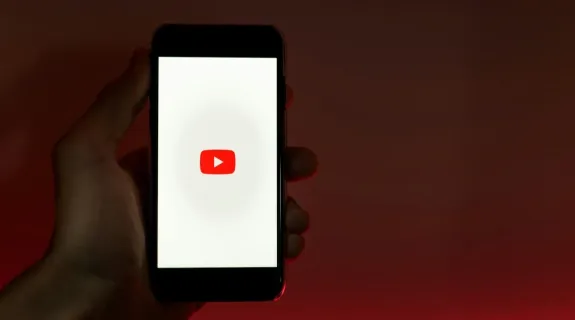 a man hold an iphone which show youtube on the screen