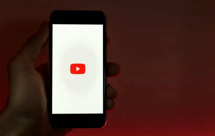a man hold an iphone which show youtube on the screen
