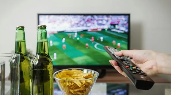 a men watching football game by using a tv remote