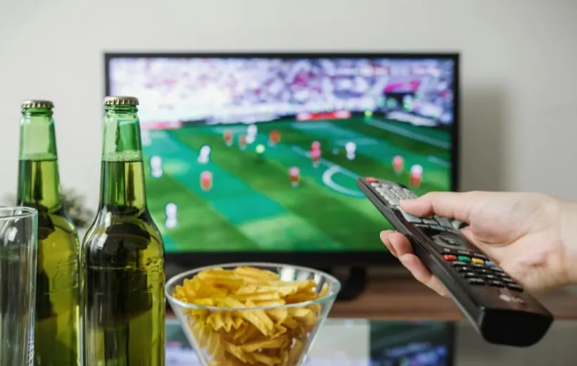 a men watching football game by using a tv remote
