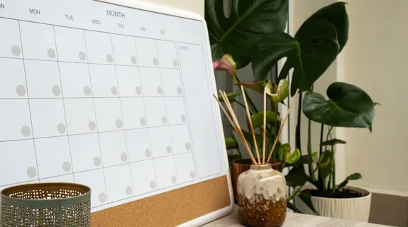 机の上にカレンダーホワイトボードマグネットと観葉植物が置いてある