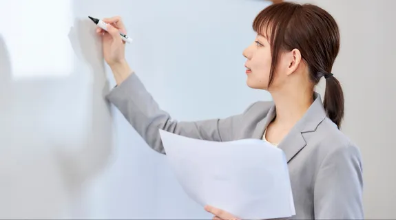 一人の女性がホーローホワイトボードに文字を書こうとしている