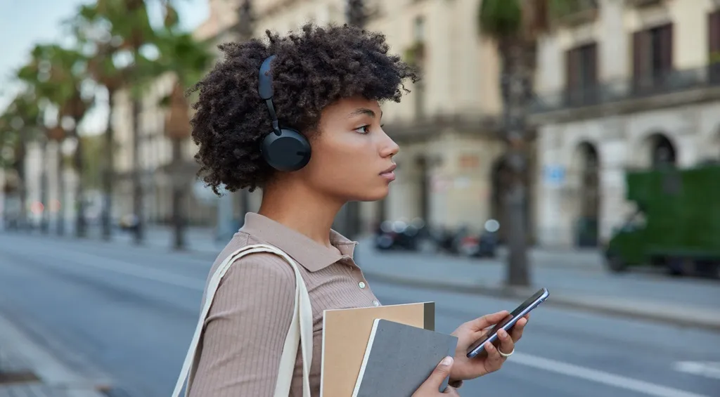 A woman wearing a noise-cancelling headset while walking outdoors.jpg