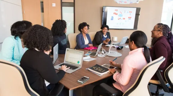 a women presents her ideas to coworkers in a huddle room