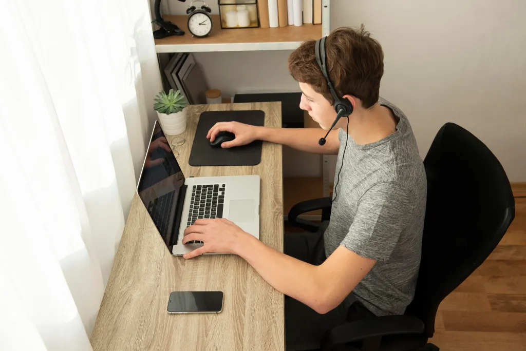 Male remote worker wearing a noise-cancelling headset, focusing on his laptop.