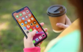 右手にコーヒー、左手にiphoneを握った女性