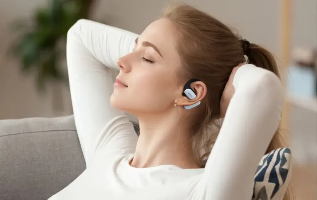 耳にかけるイヤホンをつけて音楽を聴いている女