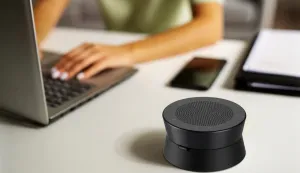 A bluetooth speakerphone next to the computer.