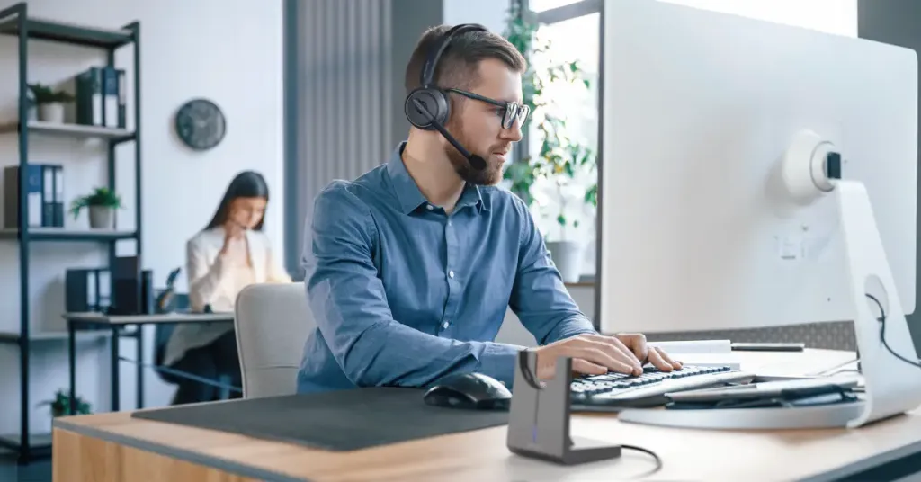 A young man wearing headphones while working on his computer.