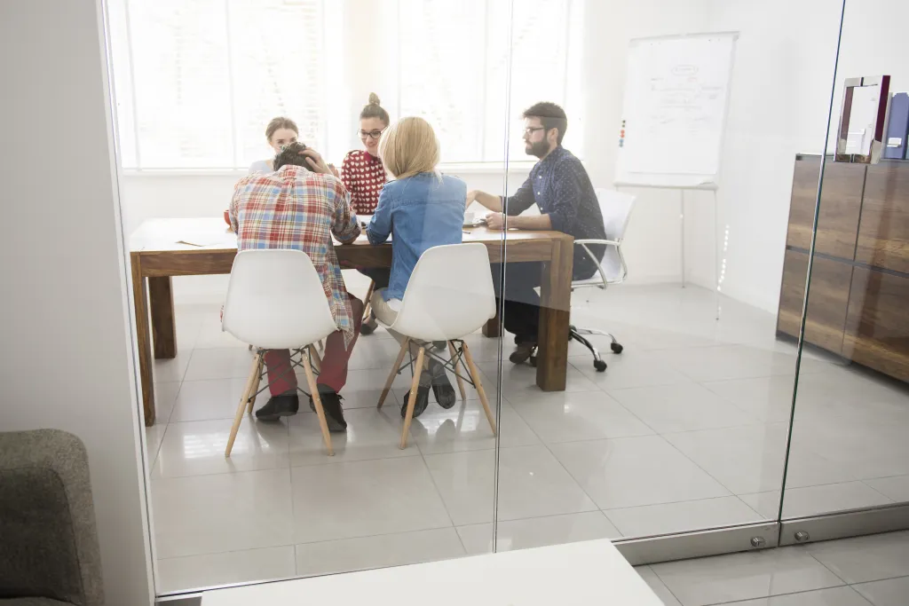 Team of professionals holding a video conference meeting in a modern glass-walled boardroom