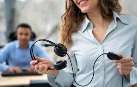 a white woman is holding a lightweight headset with mic