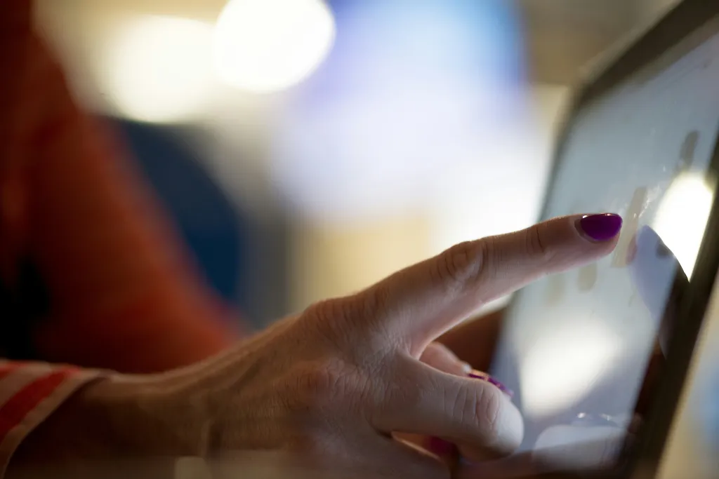 A graphic designer sketching a new UI design directly onto a high-resolution small touch screen monitor