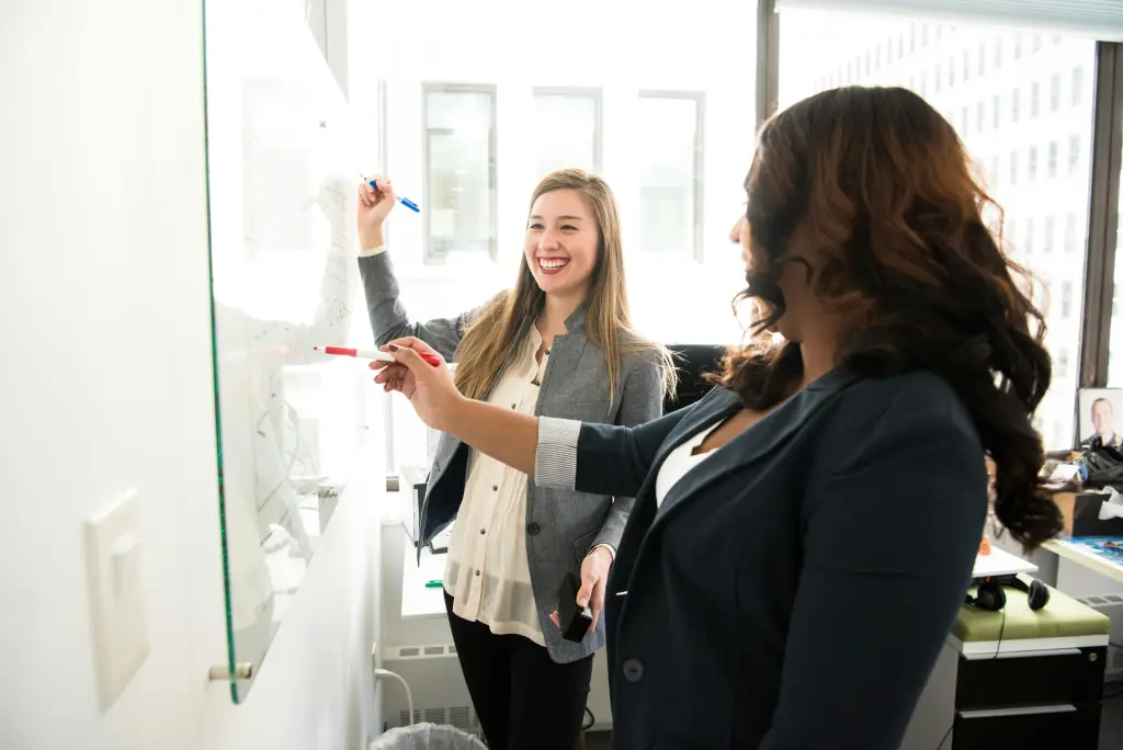 Frauen schreiben am ms whiteboard im unterricht