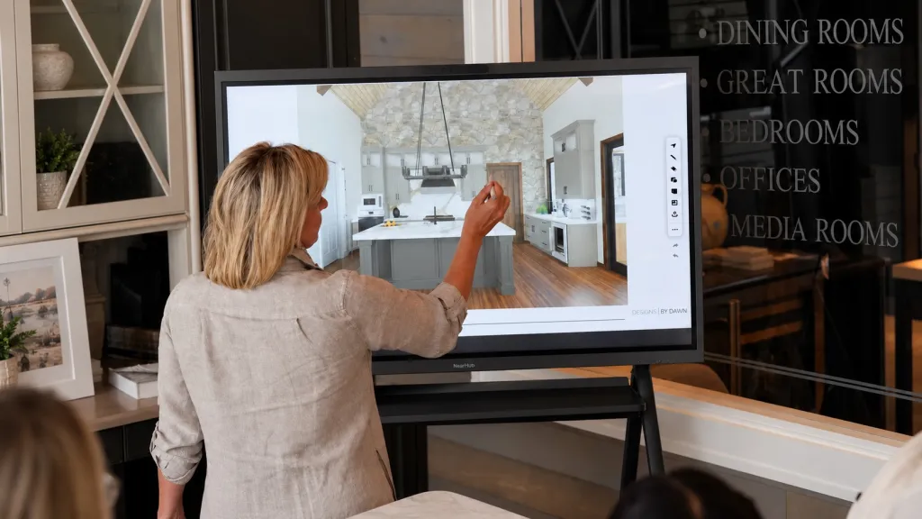A designer using a NearHub Board Max on a mobile stand to annotate an interior design rendering with a stylus, demonstrating touch whiteboarding in a collaboration session