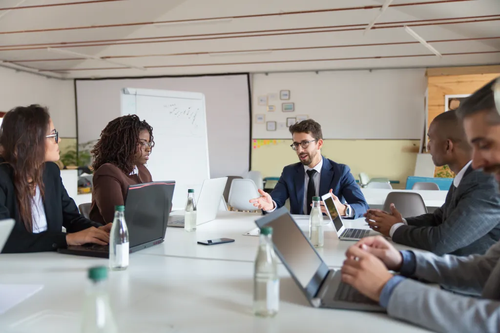 A group of business professionals having a meeting in a large boardroom equipped with a professional PTZ camera and video bar system.