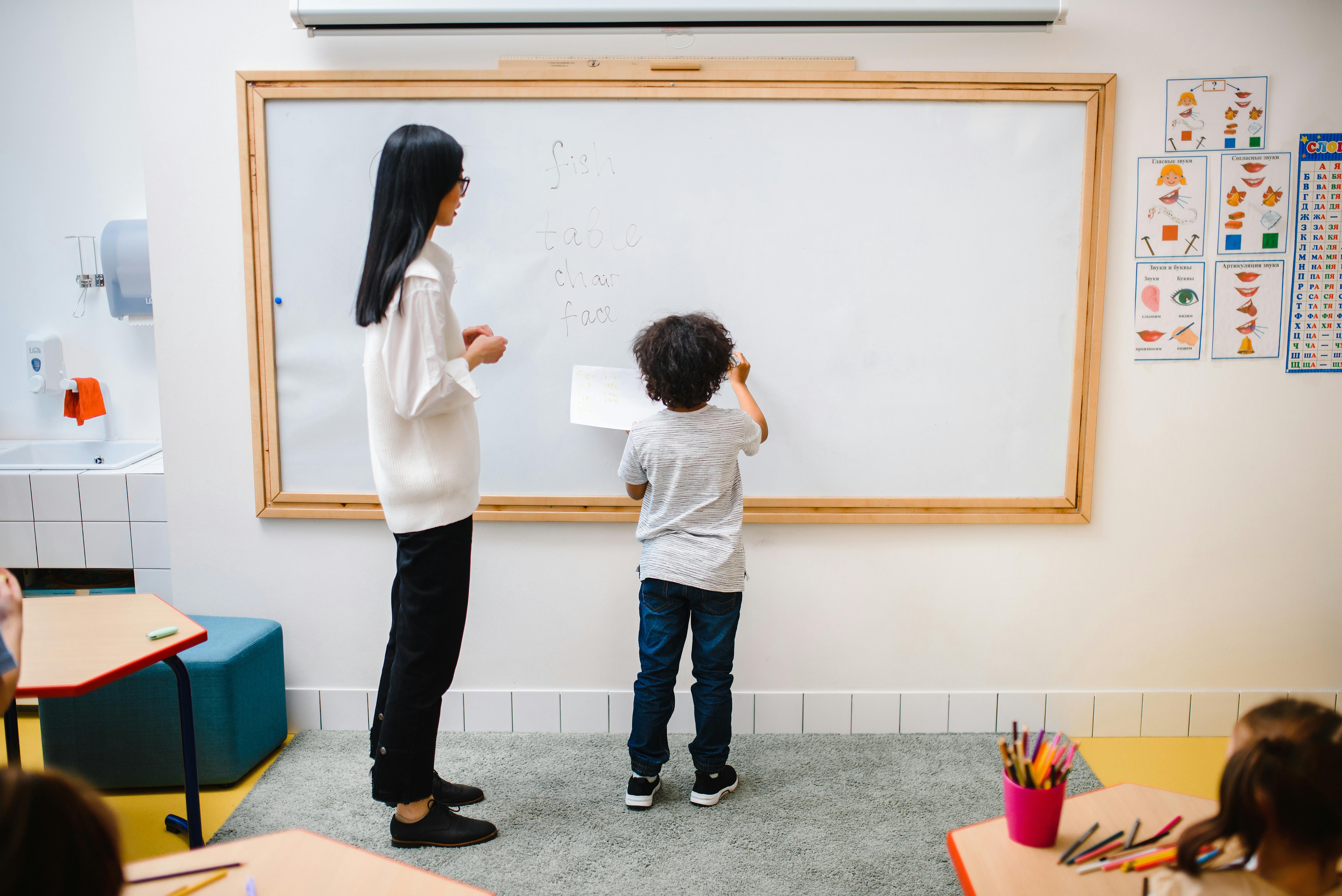お母さんと息子が壁面ホワイトボードで字を書いています