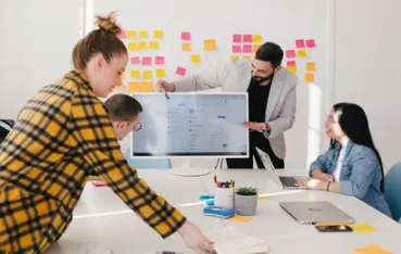 A creative team collaborating on a 30-inch touch screen monitor