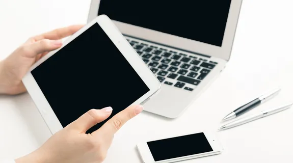 一人がデジタルメモを手に持ち、そばにパソコンとスマホがある