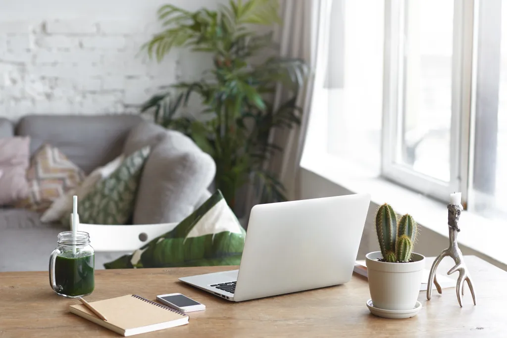 Professional remote work set up with dual monitors, plants, coffee, and a headset to block out noise.