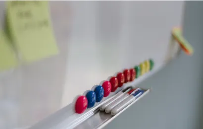 ホワイトボードの上に数本のマーカーが置かれている