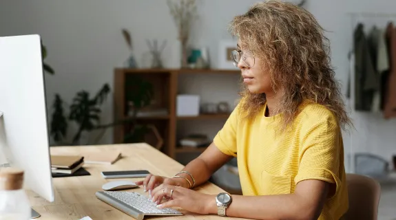 A woman sits beside a desk showing ergonomics in computers