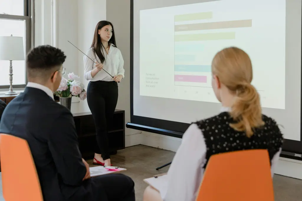A presenter stands in front of a smart board projector for a classroom  casting a large disruptive shadow over the lesson material on the screen