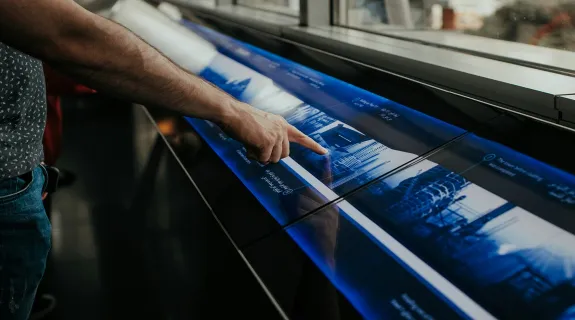 A small team brainstorming ideas together on a small touchscreen in a creative huddle room