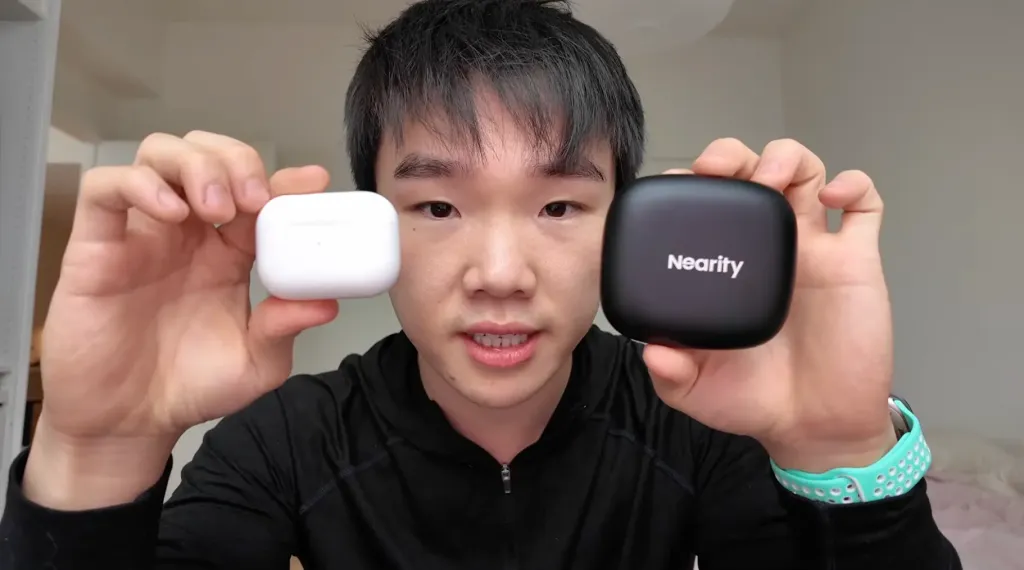 Jason Huang holding the Nearity Menpod Fit 2 open ear headphones in one hand and AirPods in the other, comparing design, weight, and ergonomic differences between the two headphones.