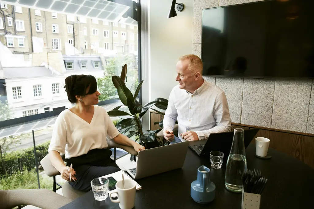 Team members in an office using a white board for a conference room to collaborate with remote colleagues