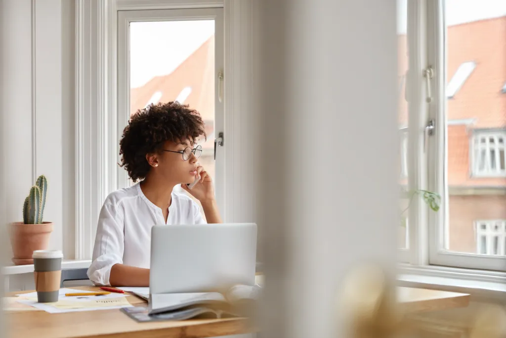 Alt text: A woman working from home sitting at her desk, using her laptop's built-in camera for a remote video call.