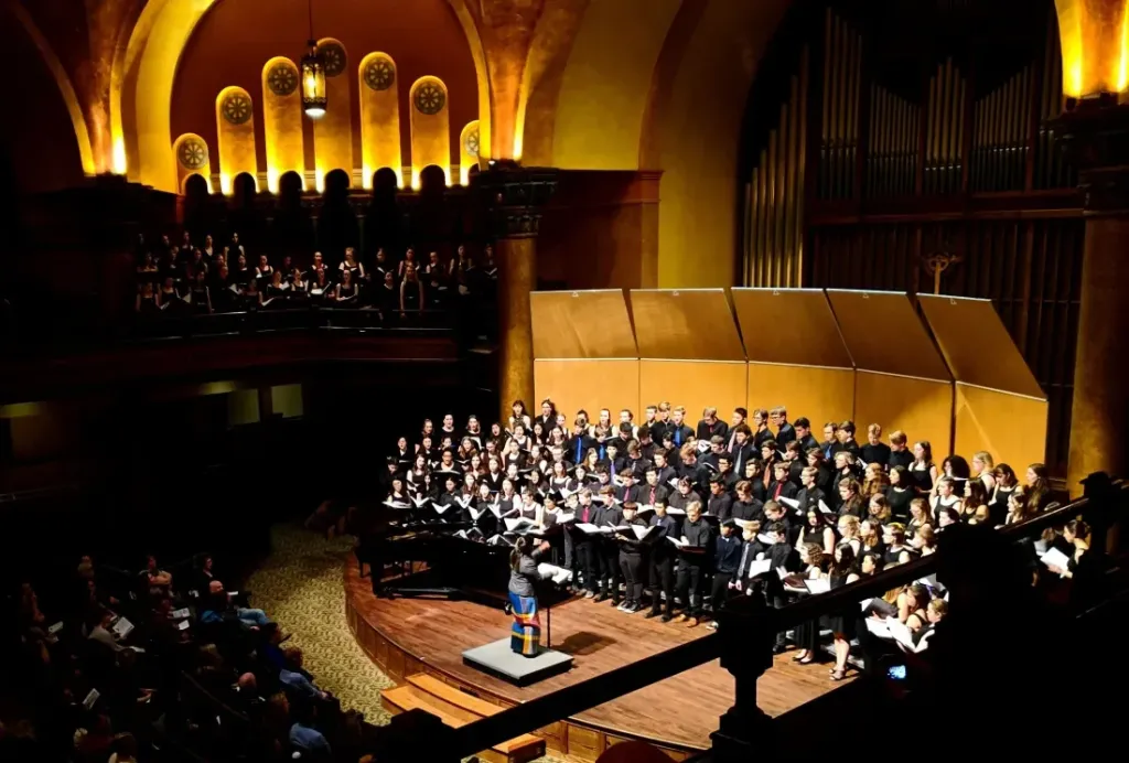 A school auditorium stage with warm lighting, ready for a performance to be streamed to families at home