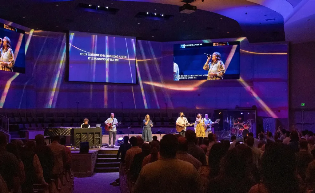 Three professional streaming cameras set up in a modern church sanctuary for multi-angle live streaming