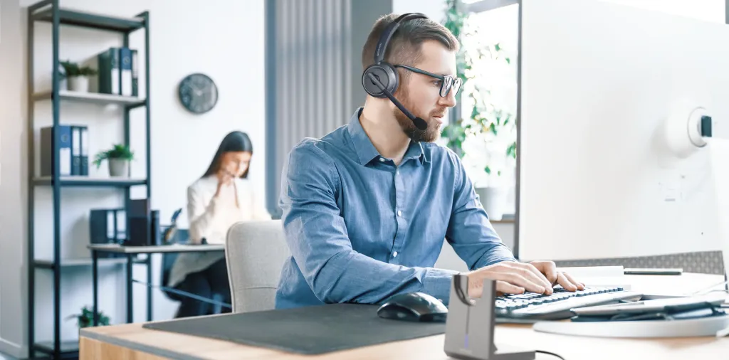 A legal intake specialist wearing a professional noise-canceling headset while typing in a busy office environment.