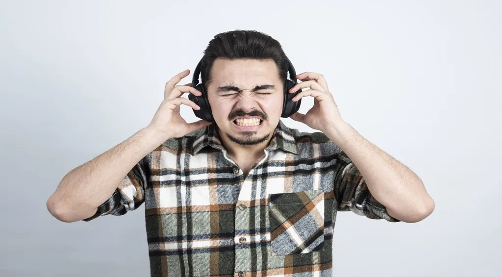Man covering his ears while wearing headsets
