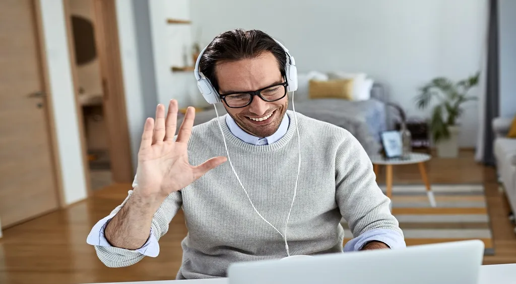 Man wearing headphones during a video meeting while working from home