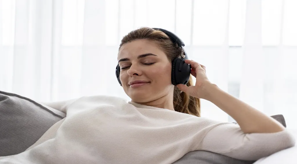 Relaxed young woman listening to high-fidelity music using comfortable headsets