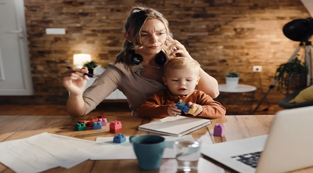 Remote working mother multitasking while caring for her child at home